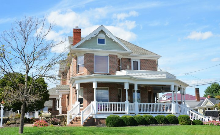 Two-story brick house with a white wraparound porch